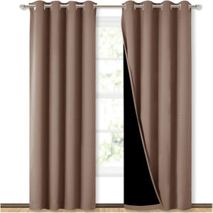 Taupe blackout grommet curtains with black thermal lining on a silver rod in front of a window.