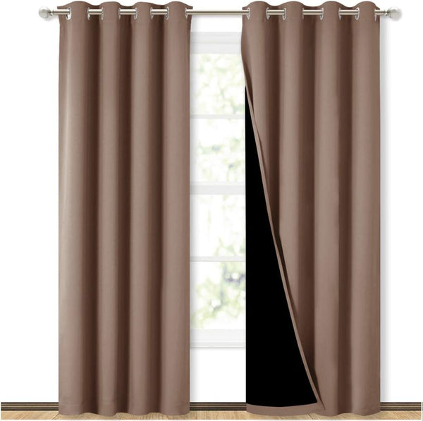Taupe blackout grommet curtains with black thermal lining on a silver rod in front of a window.