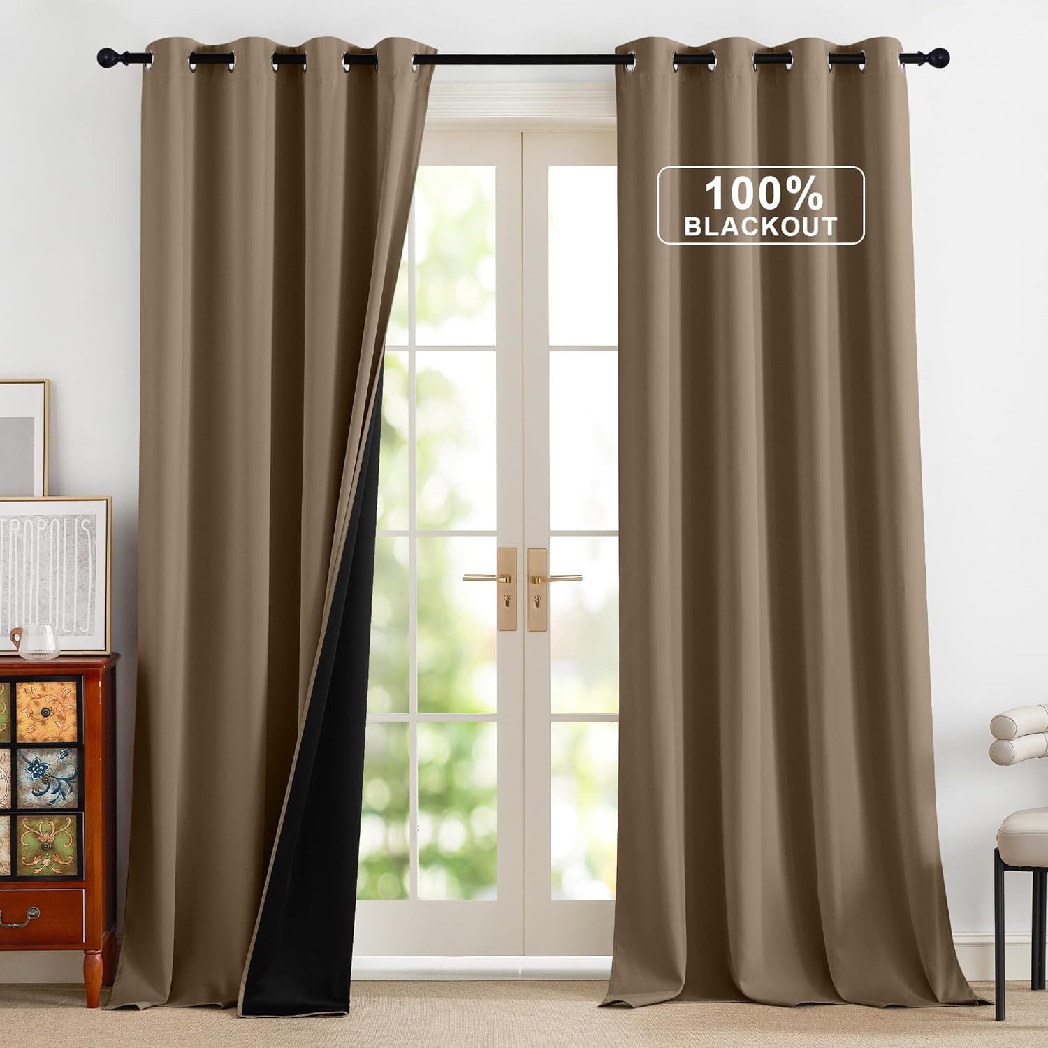 A pair of taupe brown blackout curtains with grommet tops hangs over a french door. The left panel reveals the black thermal lining.