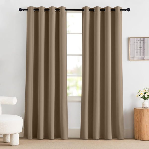 Taupe solid blackout curtains with black grommet top hanging on a window rod in a bright room.