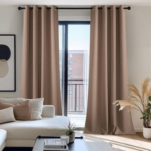 Taupe room darkening grommet top curtains frame a modern balcony door in a bright living space.