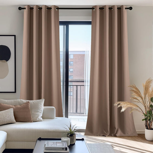 Taupe room darkening grommet top curtains frame a modern balcony door in a bright living space.