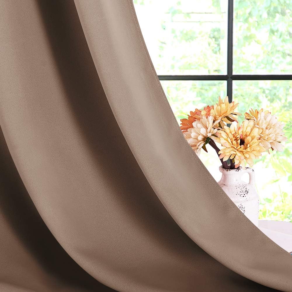 Close-up of a textured taupe solid blackout curtain panel, revealing a sunlit window and flowers.