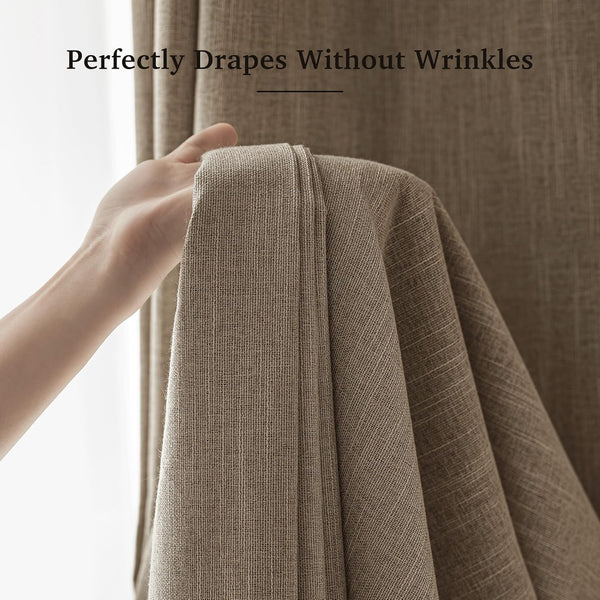 A hand holding up a section of taupe textured linen curtains, showing off the smooth, wrinkle-free drape of the fabric.