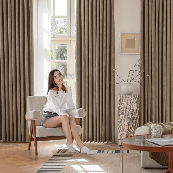 Taupe textured pleated window curtains flanking a large sunlit window in a modern living room.