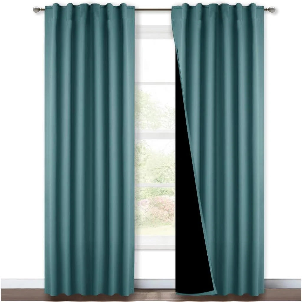 Teal rod pocket blackout curtains with black lining hanging over a bright window