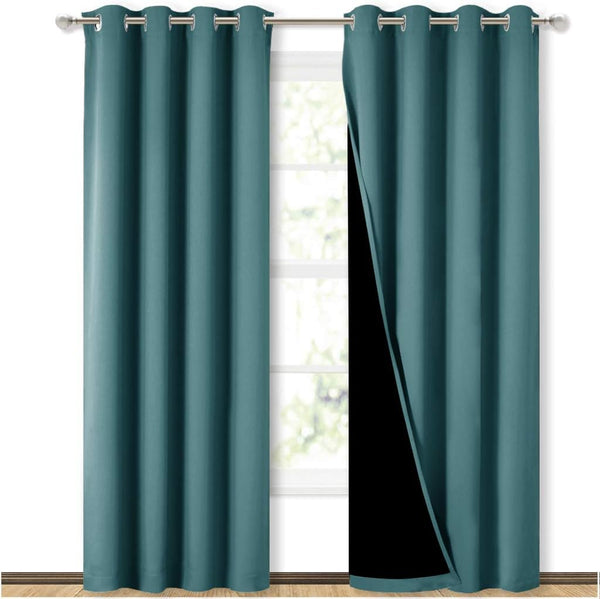 Teal blackout curtains with silver grommets hanging on a rod. One panel is open, showing the dark lining.