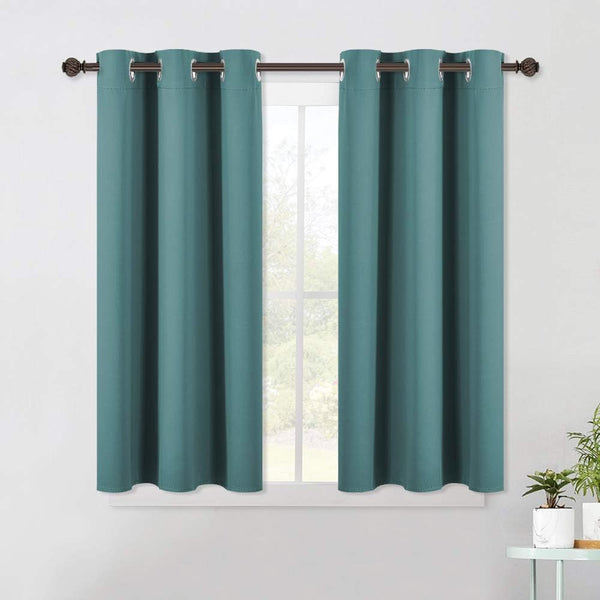 Teal blackout curtains with silver grommet tops hang on a dark brown rod over a white window frame.