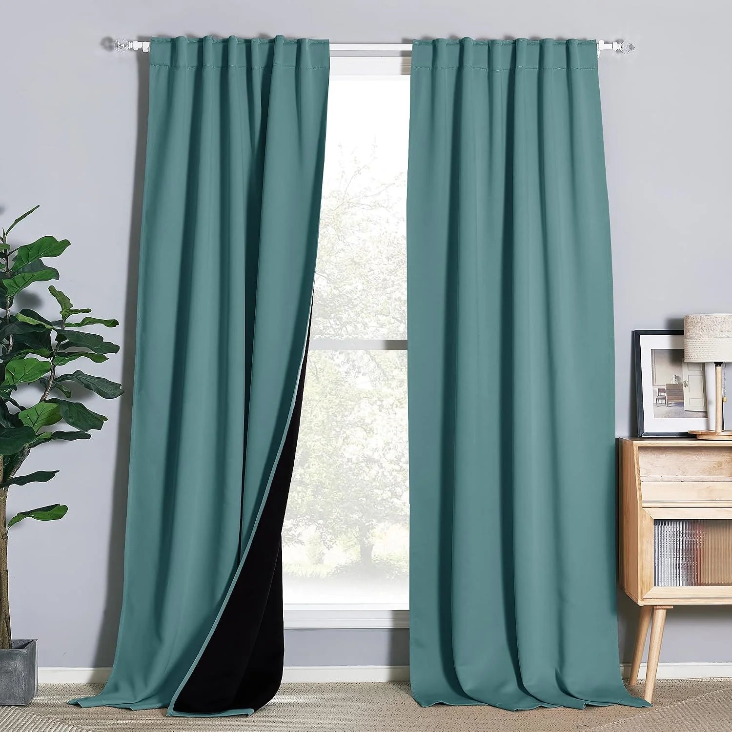 Teal blackout curtains on a white rod in a modern room, one panel pulled back