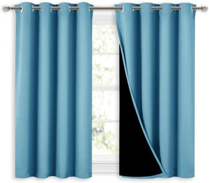 Teal blue blackout curtains with silver grommet tops, one panel pulled back to reveal black lining, hanging over a window.
