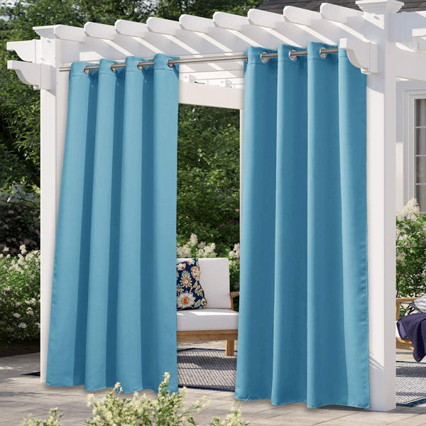 Teal blue outdoor patio curtains with silver grommets on white pergola, overlooking sunny garden.