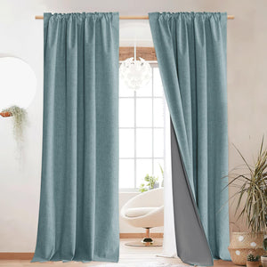 Pair of textured teal blue linen-look blackout curtains with dark grey lining, hung in a bright modern room.