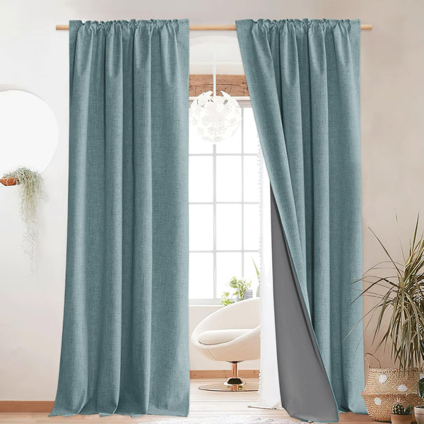 Pair of textured teal blue linen-look blackout curtains with dark grey lining, hung in a bright modern room.