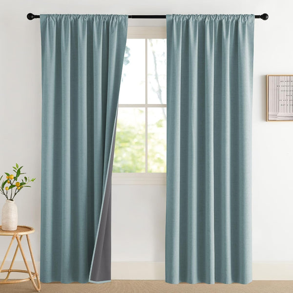 Teal blue textured rod pocket curtains with dark grey blackout lining. Hung on a black rod.