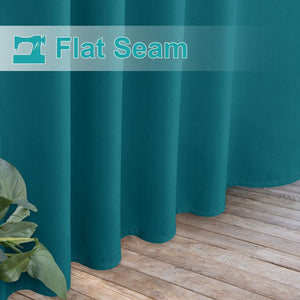 Teal curtain with a prominent flat seam and neatly stitched hem, draping onto a wooden floor.