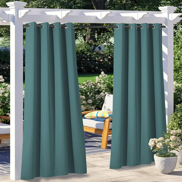 Two dark teal outdoor privacy curtains with grommet tops hanging from a white pergola, shading a patio.