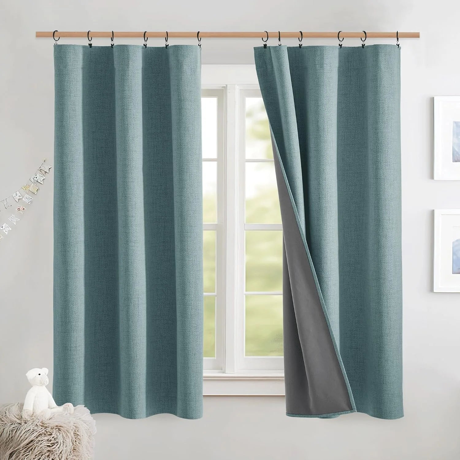 Teal textured blackout curtains with clip rings and gray lining on a bright window