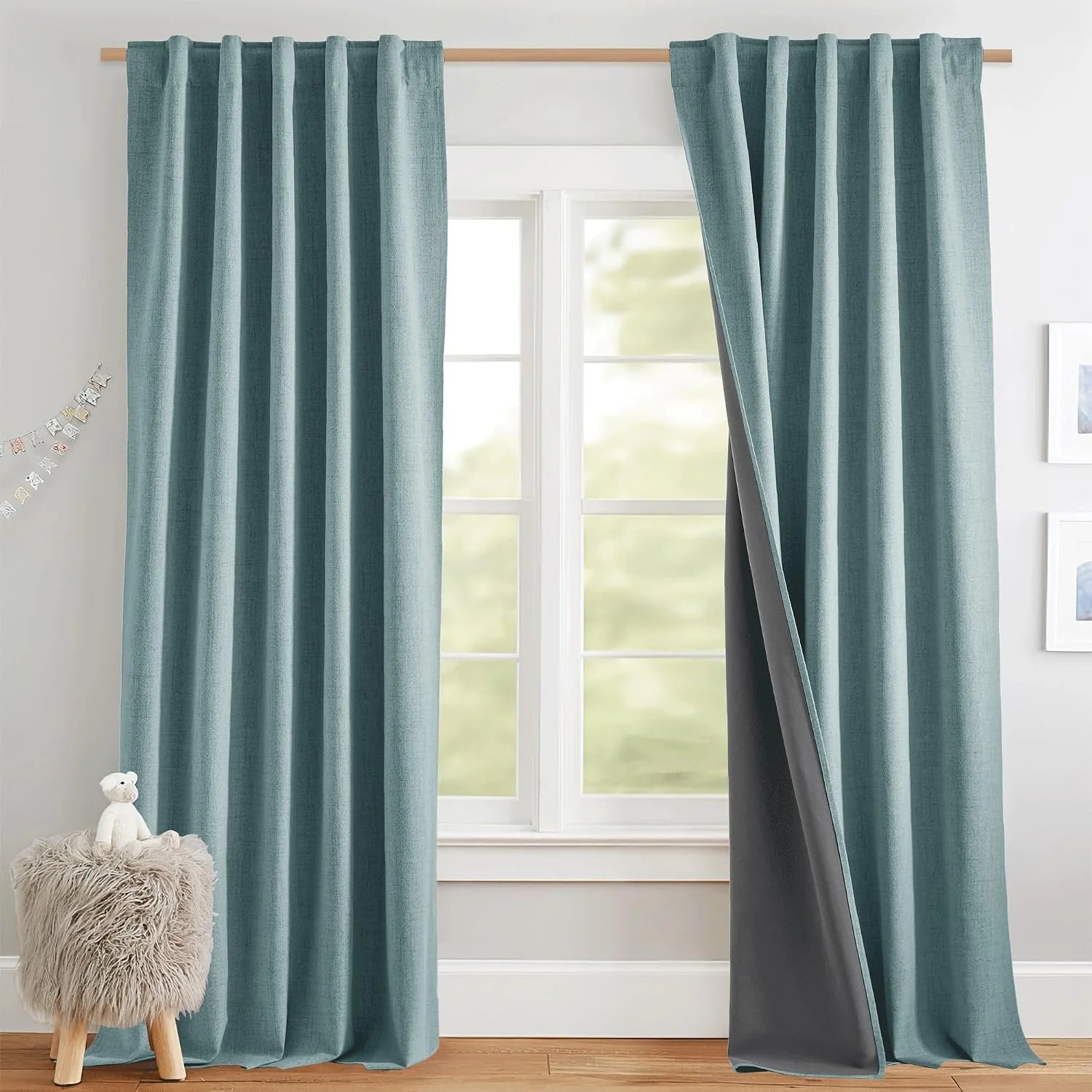Teal linen-look blackout curtains on a wooden rod in a bright modern nursery window
