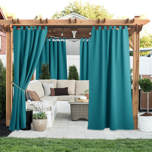 Teal tab top outdoor curtains hanging on a wooden pergola. One panel tied back for patio privacy.