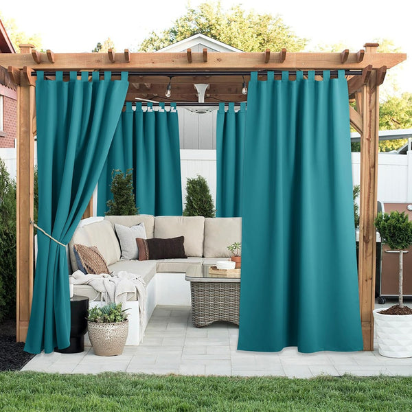 Teal tab top outdoor curtains hanging on a wooden pergola. One panel tied back for patio privacy.