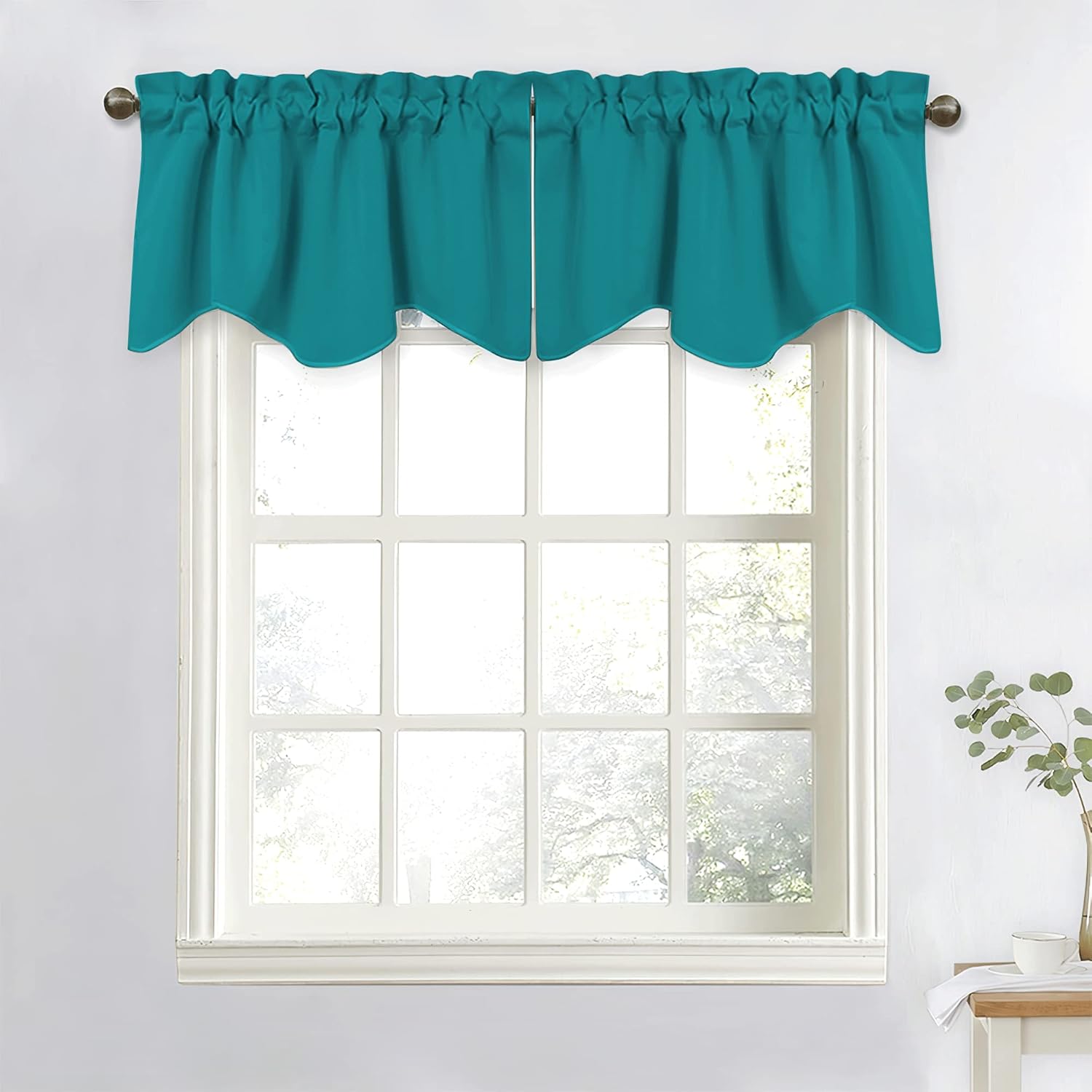 Teal blue scalloped window valance with gathered rod pocket top on a white window frame.