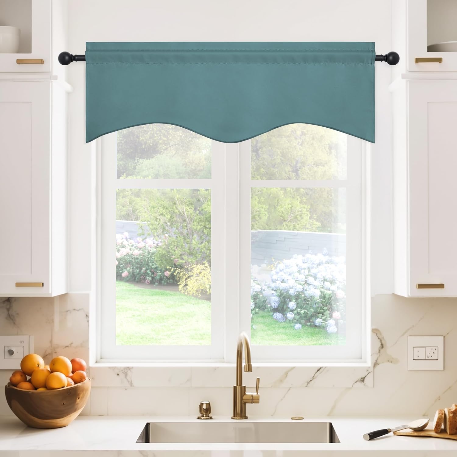 Teal blue fabric valance with scalloped hem and rod pocket hanging over a kitchen window.