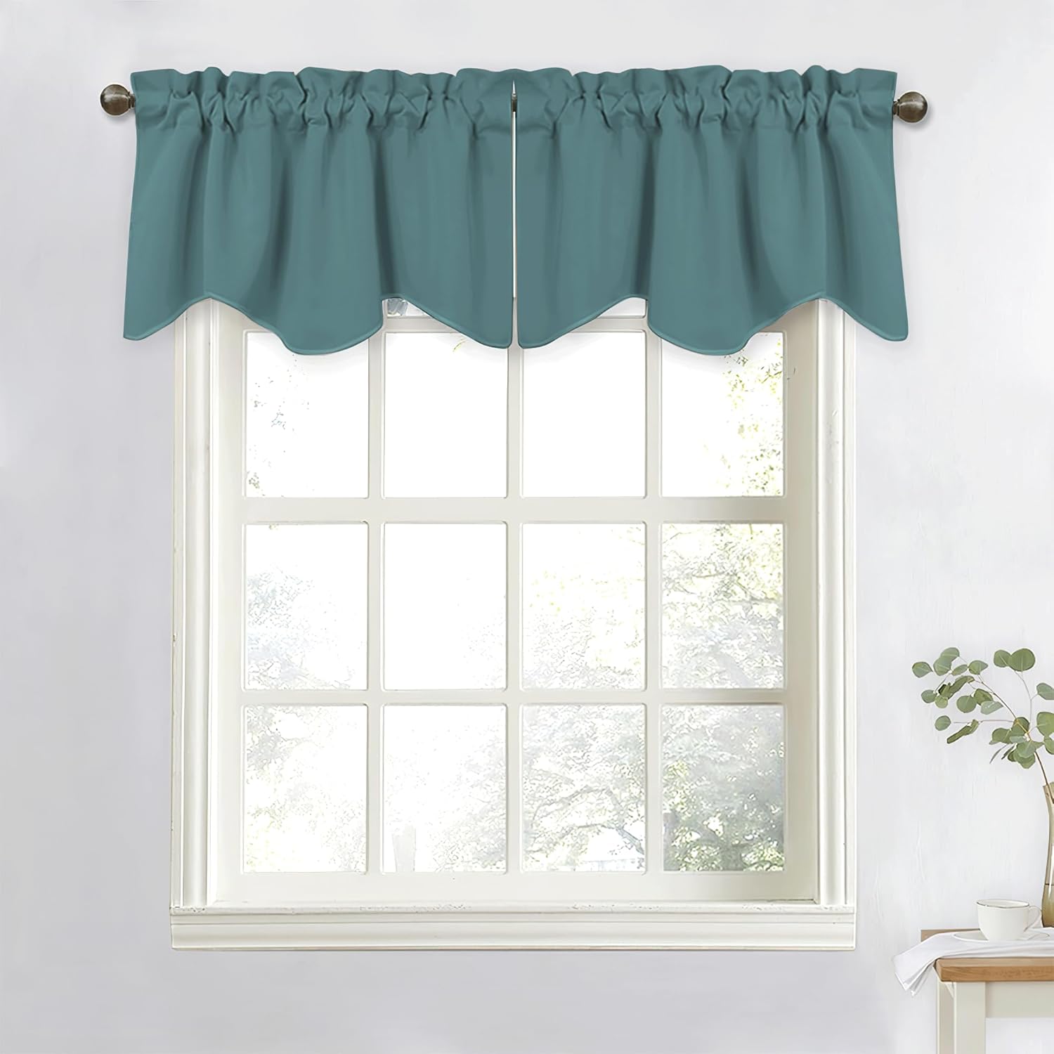 Teal rod pocket window valance with a gathered top and decorative scalloped bottom edge hanging over a window.