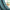 Close-up of a smooth teal solid blackout curtain panel draped beside a window with a vase of flowers.