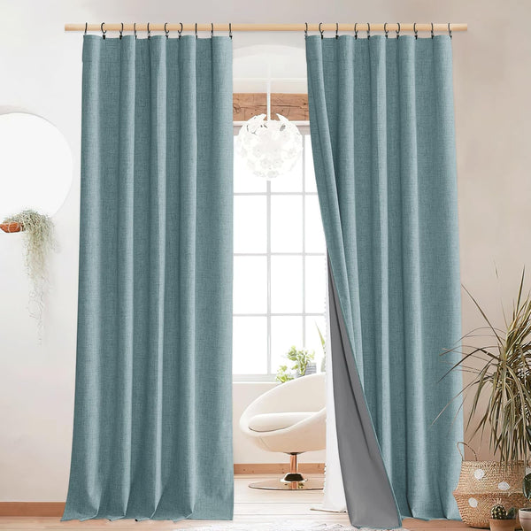 Teal blue textured blackout curtains with grey lining, hung with clip rings over a bright window.