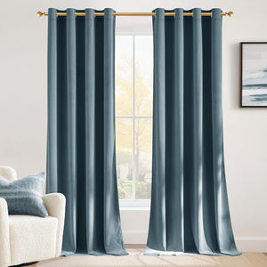 Two teal velvet blackout curtains with a grommet top hanging on a gold rod in a modern living room.