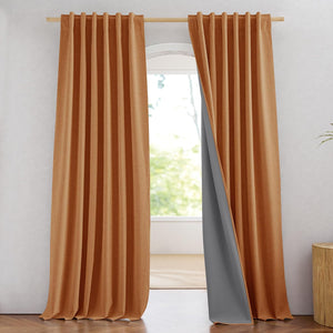 Pair of terracotta textured blackout curtains with dark grey lining hanging on a wooden rod in a modern room.