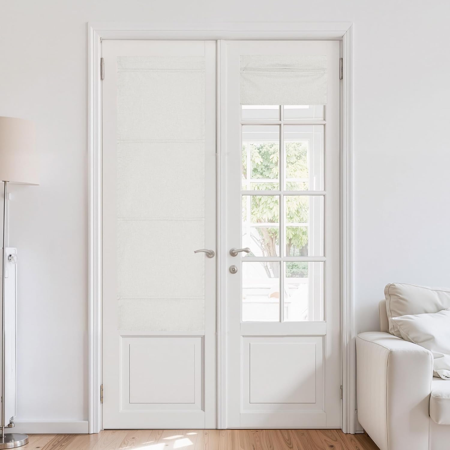 Tailored white textured roman shades on french doors, one fully extended and one partially raised, in a bright room.