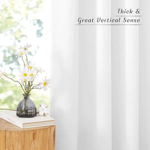 Thick pure white window curtains with excellent vertical drape, seen by a bright window.