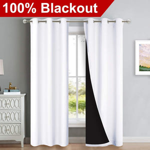 Pair of white 100% blackout curtains with silver grommets hanging on a window rod.