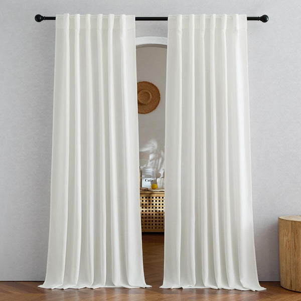 Two white back tab window curtain panels elegantly draped on a black rod, touching a wooden floor.