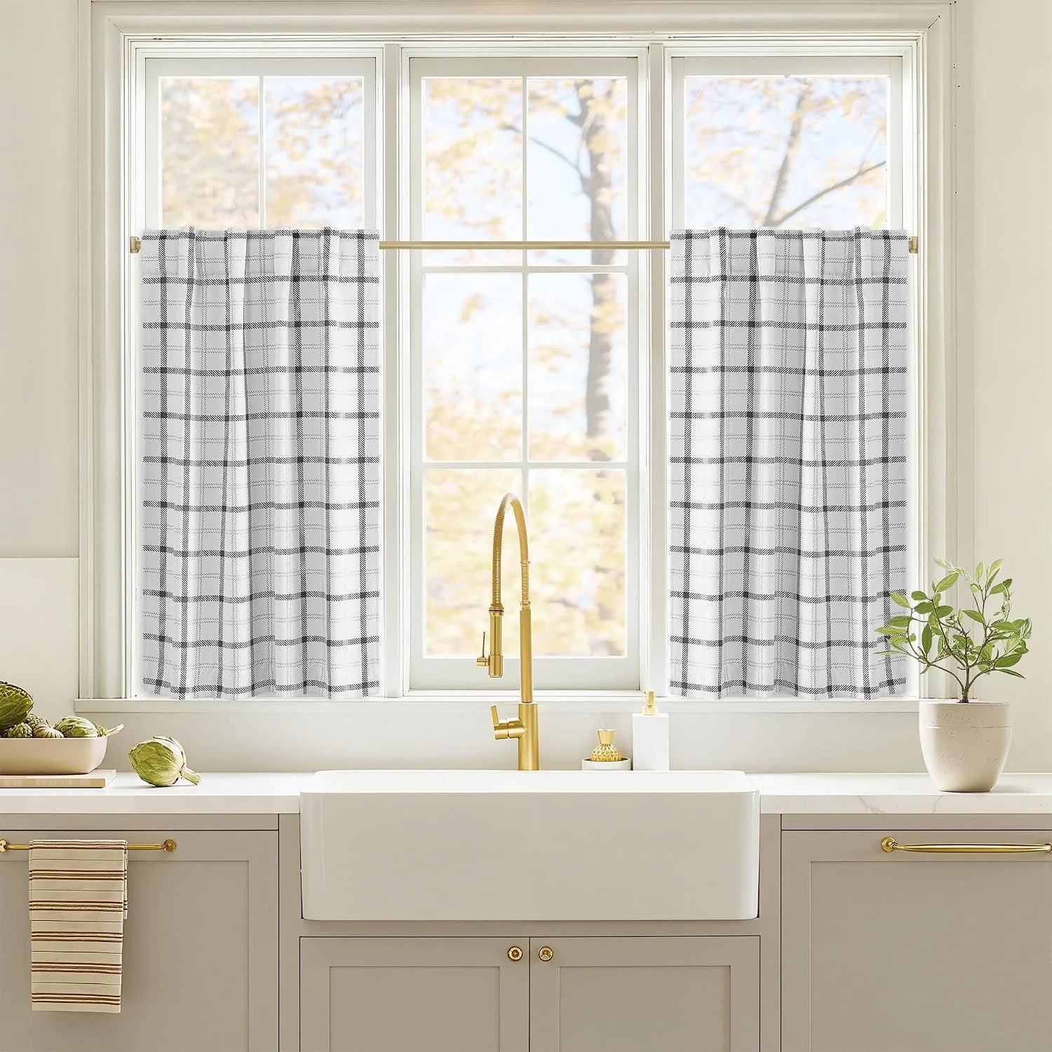 White and black plaid cafe curtains on a brass rod above a farmhouse kitchen sink