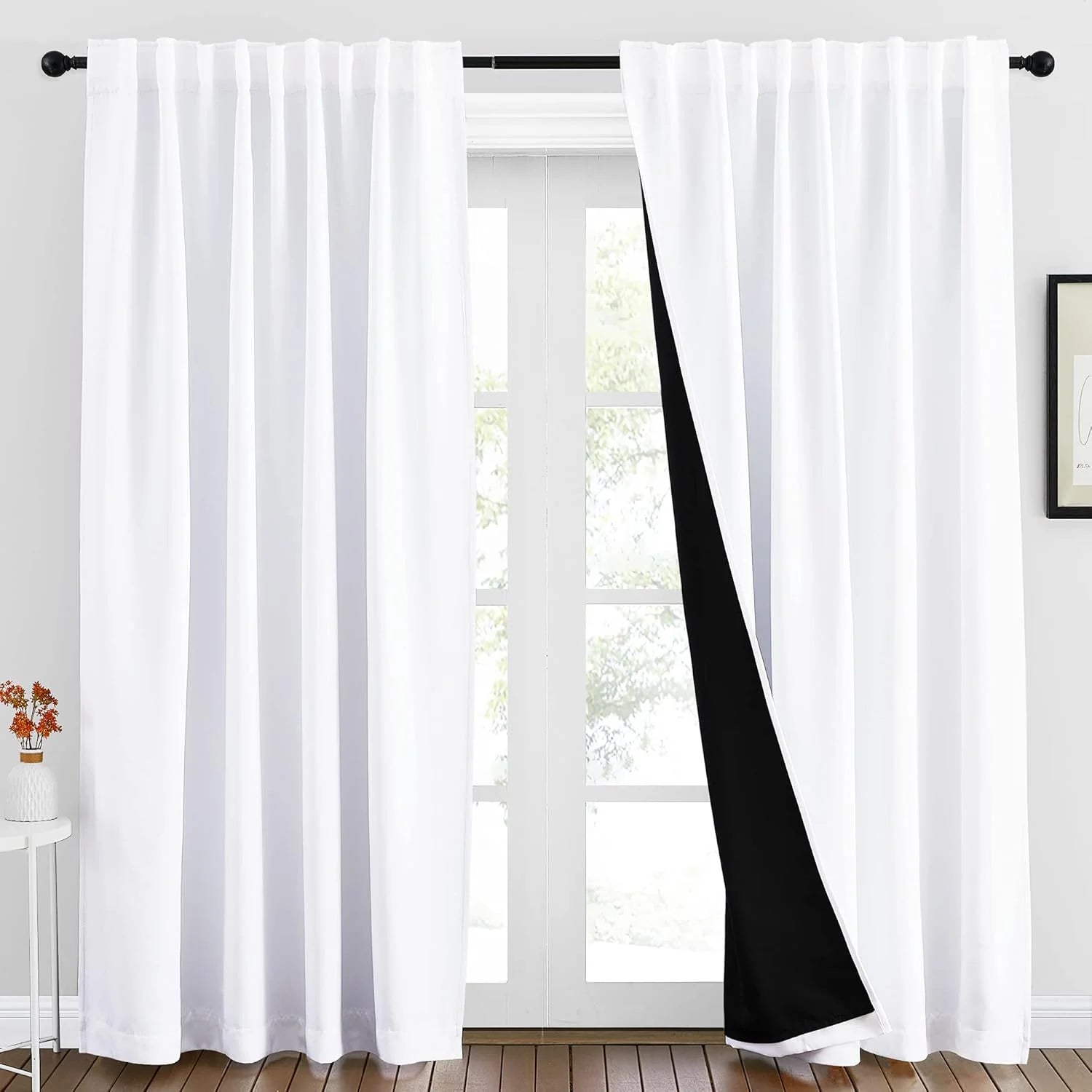 White rod pocket blackout curtains with black lining over a bright window