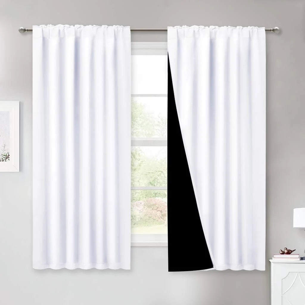 White blackout curtains with black lining on a rod in a bright modern room