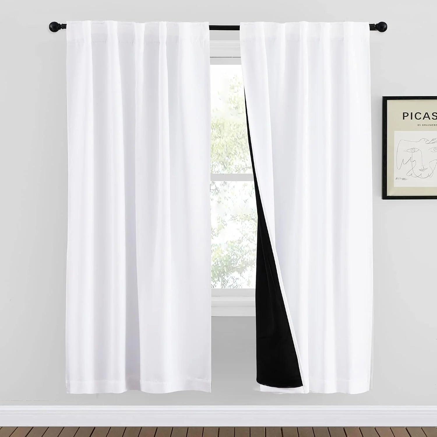 White rod pocket blackout curtains with black lining hanging in a bright modern room