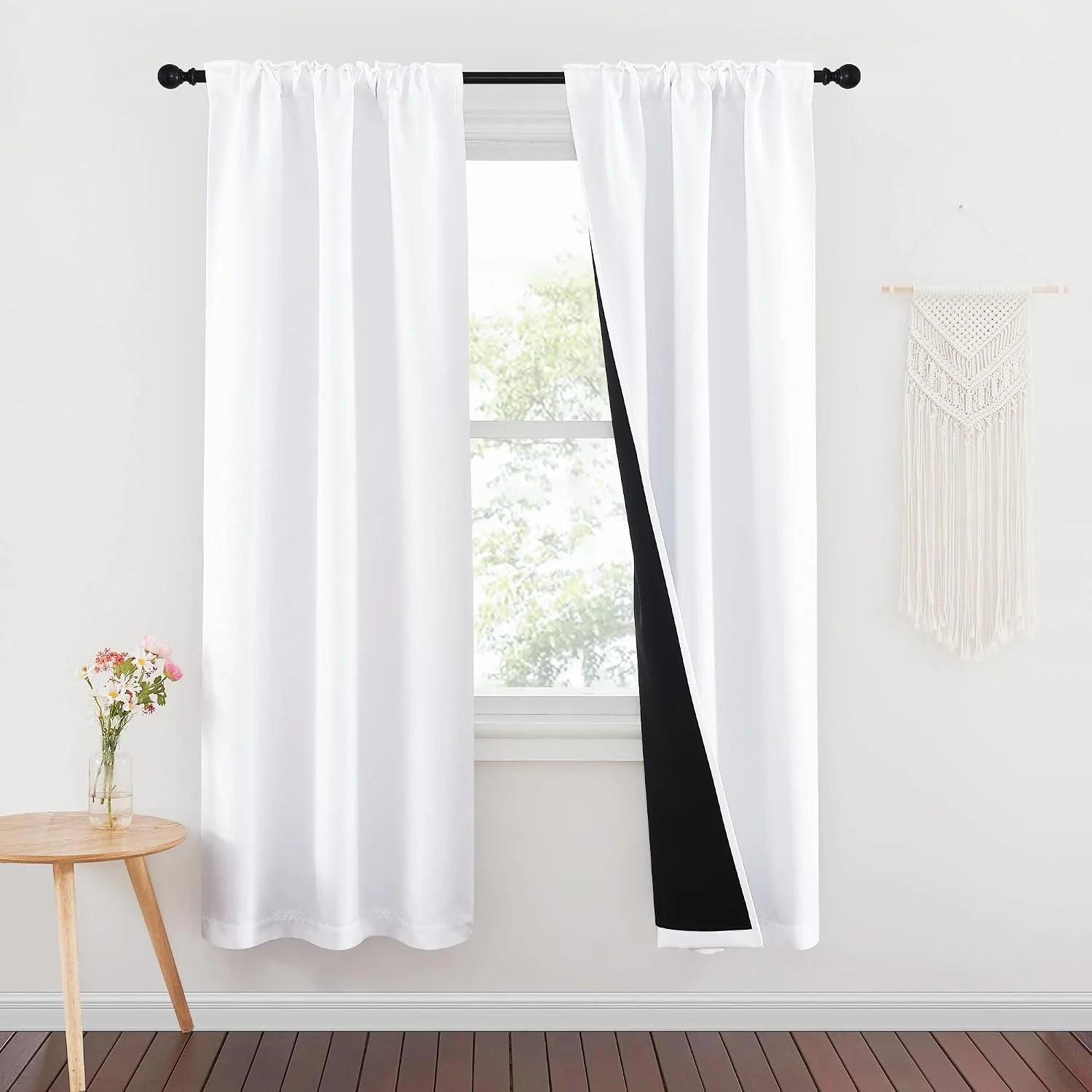 White blackout curtains with black lining on a rod in a bright minimalist room
