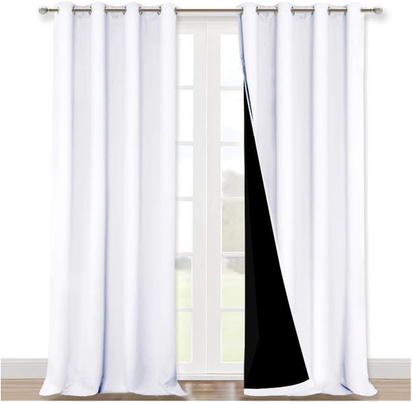 White blackout curtains with silver grommet tops hang over a window. The right panel reveals its black lining.