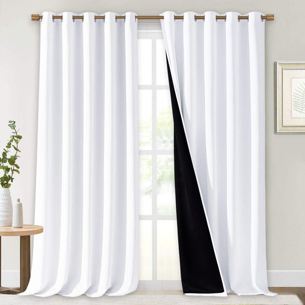 White grommet blackout curtains on a wooden rod, with one partially open revealing its black lining.