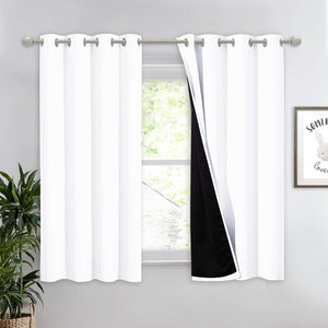 White blackout curtains with silver grommet tops on a silver rod, one panel revealing its black lining.