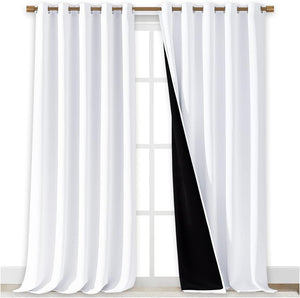 White blackout curtains with bronze grommet top hanging on a rod. Black lining is visible on the inner side of one panel.