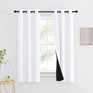 White blackout curtains with black grommet tops on a black rod, revealing dark lining in a modern room.