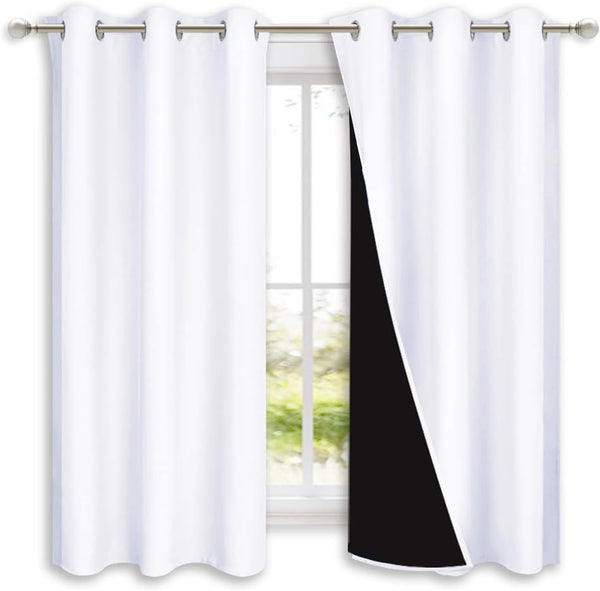 Pair of white blackout curtains with visible black lining and silver grommet tops on a window rod.