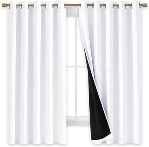 White blackout curtains with bronze grommets on a rod. One curtain pulled back shows the black thermal lining over a window.