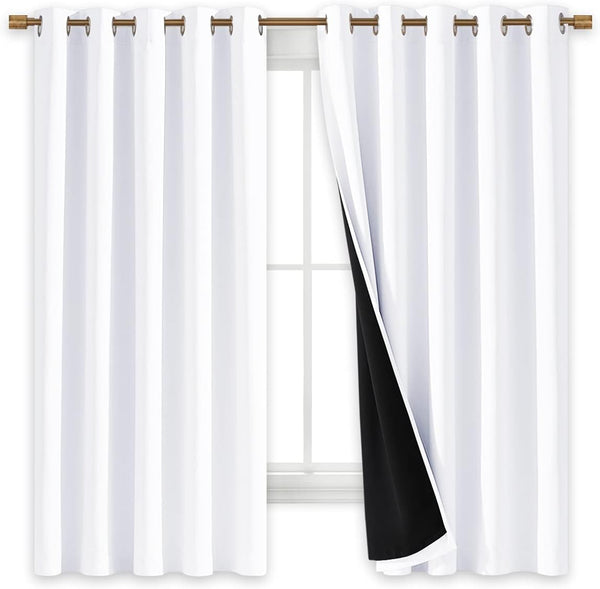 White blackout curtains with bronze grommets on a rod. One curtain pulled back shows the black thermal lining over a window.