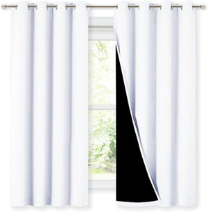 Two white blackout curtains with silver grommet tops, one pulled back to show the dark light-blocking lining.