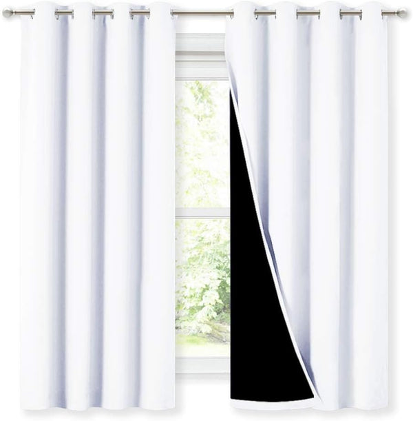 Two white blackout curtains with silver grommet tops, one pulled back to show the dark light-blocking lining.